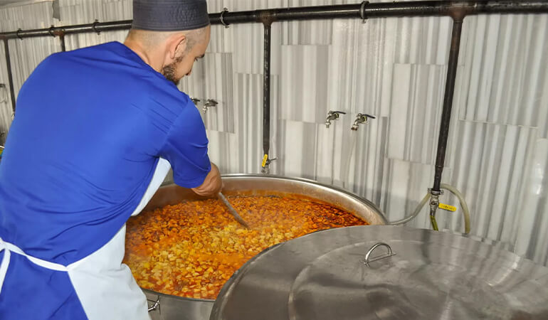 Aşevi mutfağında yemek pişiren aşçı