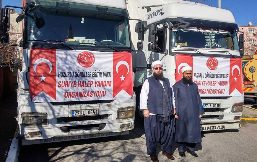 Yardım tırı önünde poz veren vakıf sorumluları